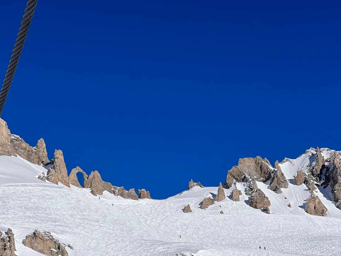 Rock spires standing out of a wide snowfield under a deep blue sky