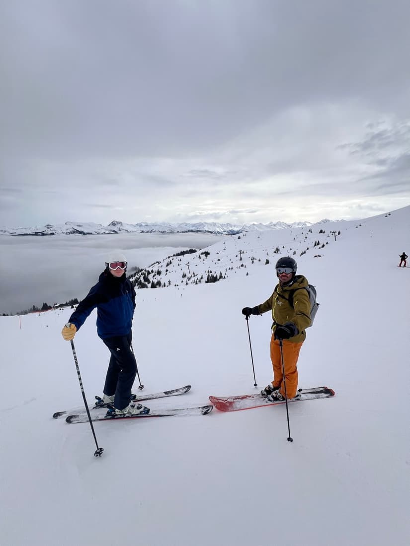 Two skiers on a slope above a sea of cloud filling the valley